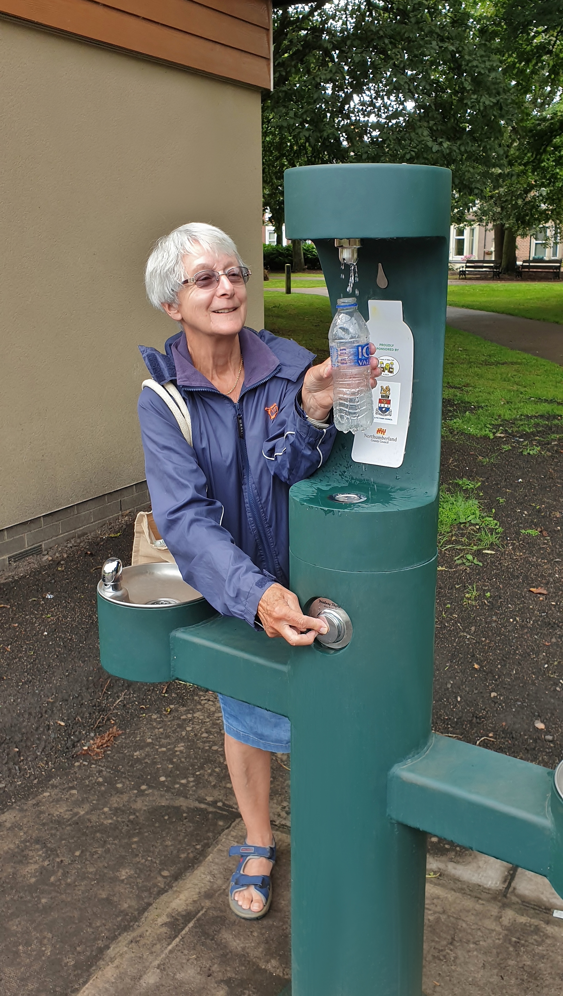 An elderly woman refilling her water bottle at the new drinking fountain.