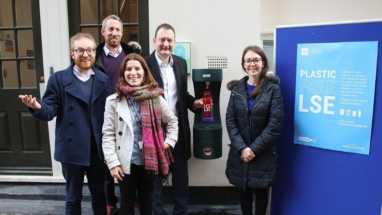 Group of people smiling at the new London School of Economics drinking fountain.