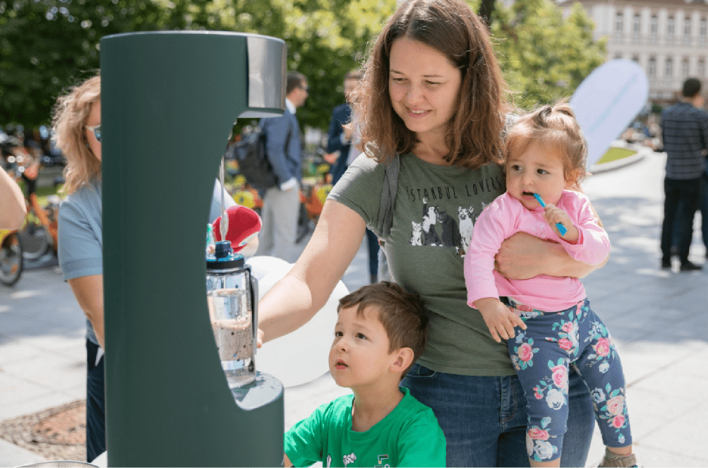 A mother with two cute children topping up her water bottle at the new drinking fountain.